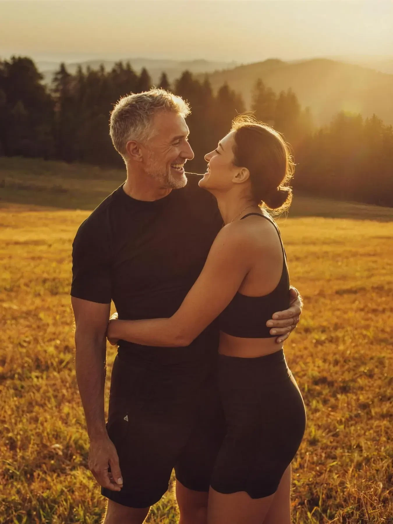 A couple embracing in a golden meadow at sunset